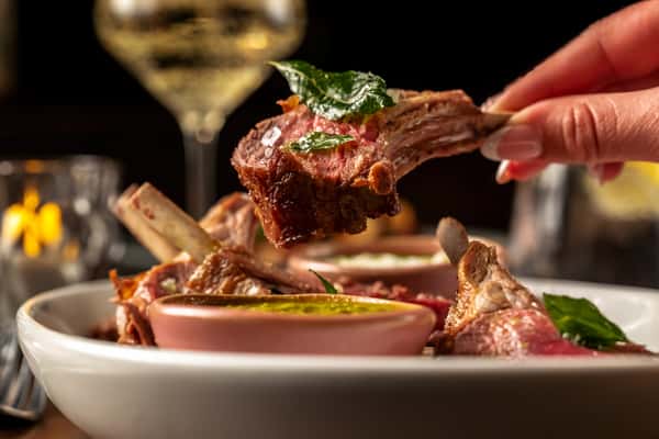 Tender grilled lamb chop served over a savory accompaniment, presented in an upscale dining setting.