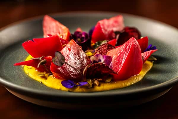Artfully plated chocolate dessert with fresh strawberries, berry sauce, and edible flower garnish.