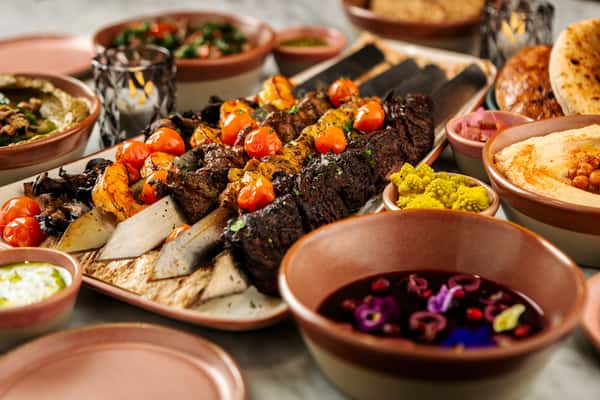 Mediterranean mixed grill platter with kebabs, roasted vegetables, dips, and colorful seasonal accompaniments.
