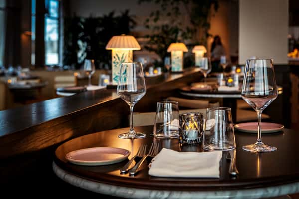 Elegant restaurant dining table with candlelight, wine glasses, and warm ambient bar lighting.