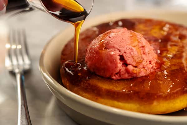 Warm caramelized dessert topped with berry sorbet as rich sauce is poured tableside.