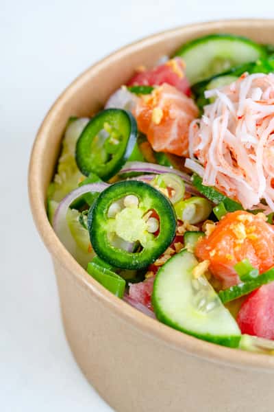 Fresh poke bowl with cucumber, jalapeño, salmon, imitation crab, red onion, and green onions