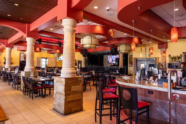 Spacious Mexican restaurant dining room with colorful décor, stone columns, full-service bar, and comfortable seating for groups.