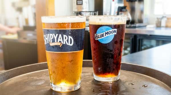 Image 3: Two refreshing draft beers are poured into branded glasses, one light and golden, the other dark and rich, perfect for pairing with seafood and casual dining.
