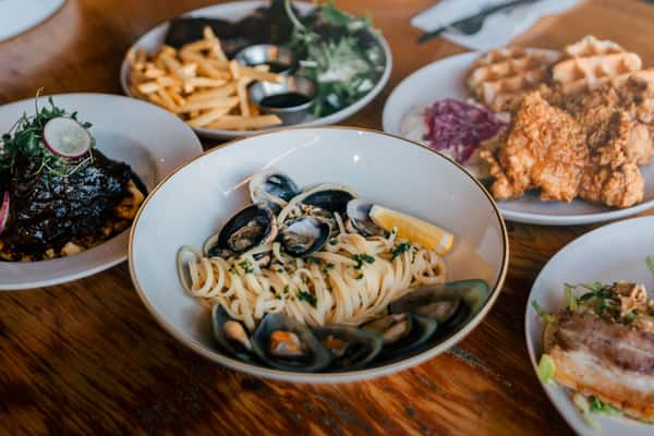 A selection of delectable dishes including pasta, fried chicken, and waffles ready to be enjoyed.