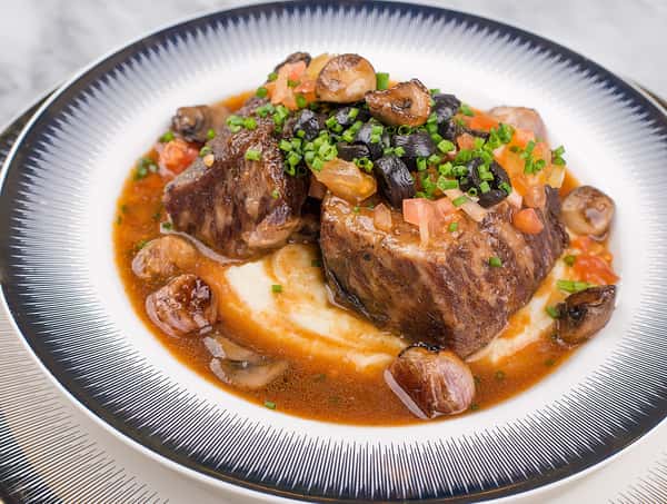Succulent braised beef short ribs with mushrooms and chives on mashed potatoes.
