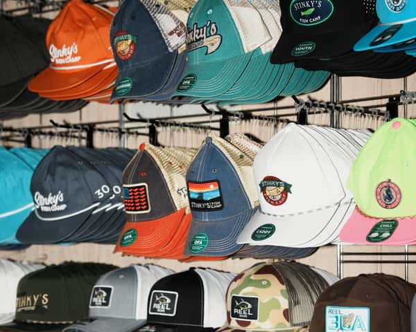Stinky's Fish Camp and related coastal brands, arranged on racks above souvenir mugs and retail items in a gift shop area.