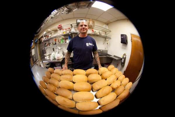 fish eye lense of employee standing in front of rolls on table