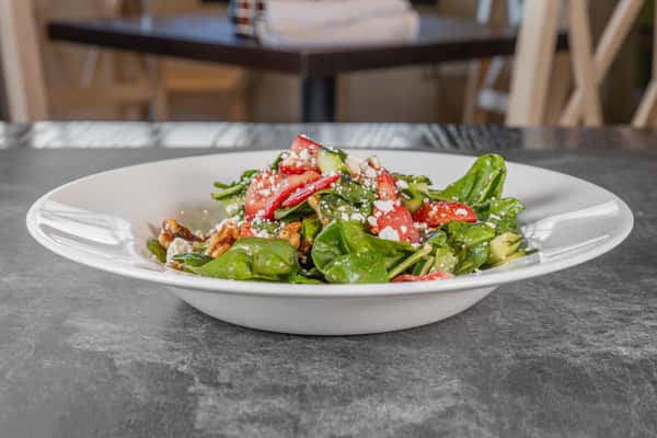 Fresh garden salad featuring mixed greens, sliced tomatoes, cucumbers, and colorful vegetables, served on a white plate.