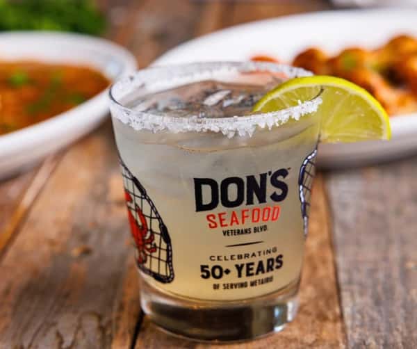 A house margarita with a salted rim and lemon garnish