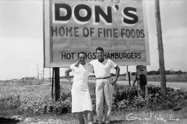 Black-and-white roadside sign reading "Don's Home of Fine Foods" with a couple posing in front, highlighting the restaurant's early branding and Grand Isle, Louisiana roots