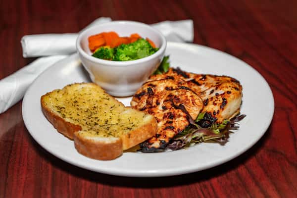 Grilled chicken breast served with garlic toast and a side of steamed broccoli and carrots.