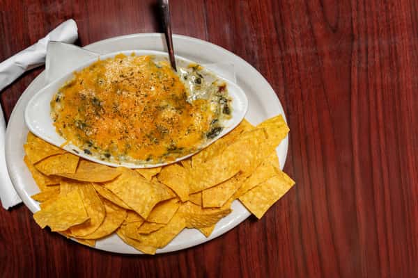 Creamy spinach and cheese dip served hot with a side of crispy tortilla chips.
