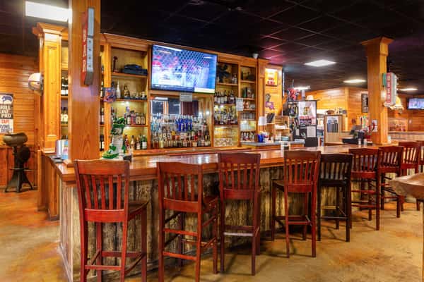 Rustic wooden bench with wagon wheel sides set against a distressed American flag backdrop inside a country-style restaurant.