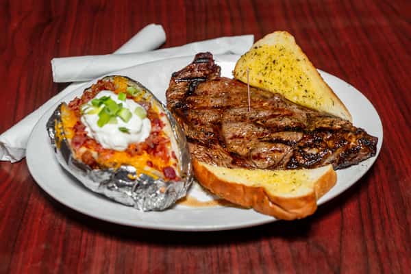 Grilled steak with baked potato topped with sour cream, cheese, bacon, and scallions, served with garlic bread on a white plate.