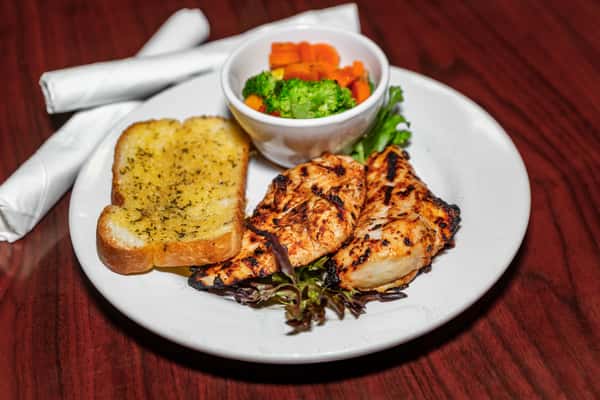 Grilled chicken breast served with garlic toast and a side of steamed broccoli and carrots.