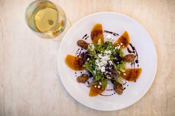 A vibrant roasted beet salad topped with creamy cheese and herbs, beautifully arranged for a fresh and colorful presentation.