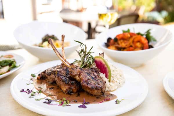 A gourmet rack of lamb, perfectly seared and garnished with rosemary, served alongside rich sides for a sophisticated main course.