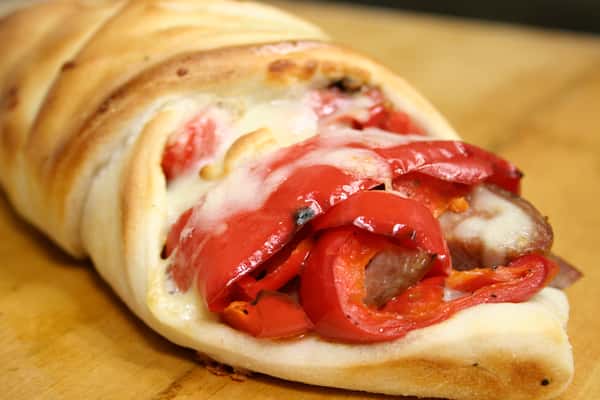 Stromboli with peppers, sausage, and cheese on wood table