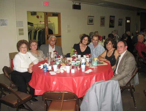Family at table with red table cloth posing for a picture
