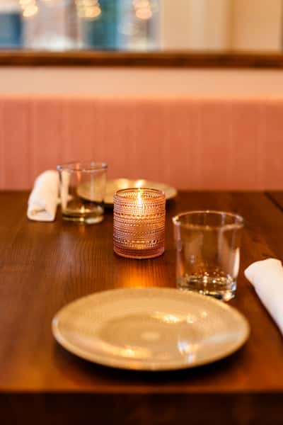 Glass votive candles sitting on a dark wood dining table