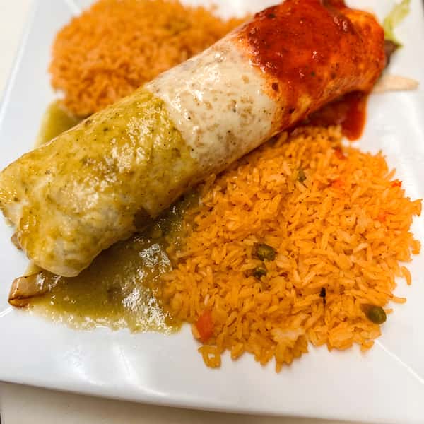 Smothered burrito topped with sauce, served with rice on the side.