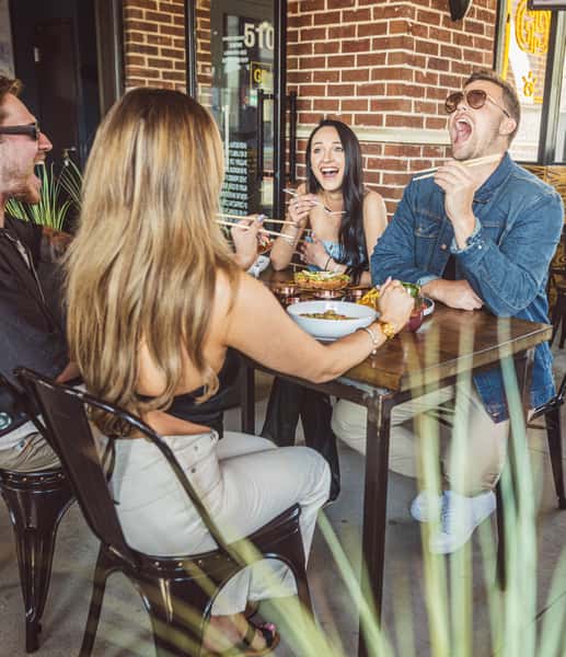 PEOPLE SITTING IN A DINING TABLE TALKING AND LAUGHING