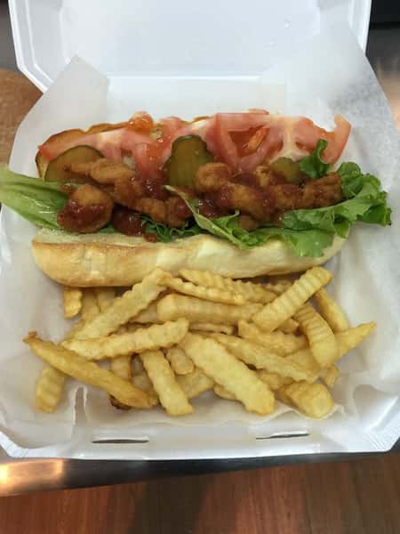 Fried shrimp poboy with side of fries in styrofoam container