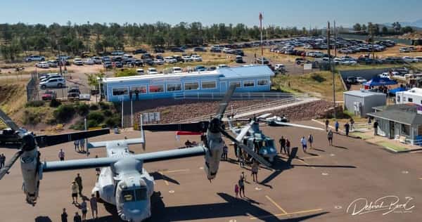 Aerial view of Crosswinds Restaurant at Payson Airport, with military aircraft on display and a large crowd attending an outdoor aviation event.