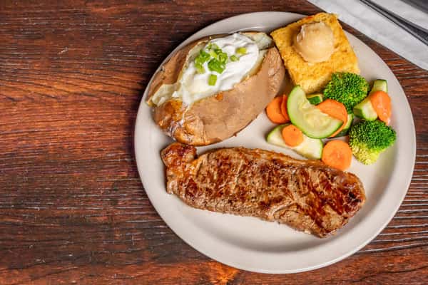 Grilled steak served with a baked potato topped with sour cream, cornbread, and steamed mixed vegetables.