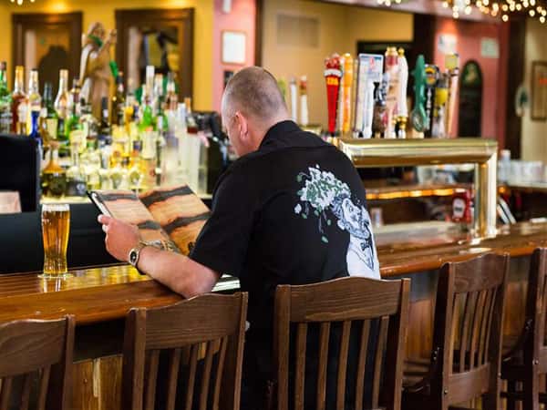 male at bar looking at a menu