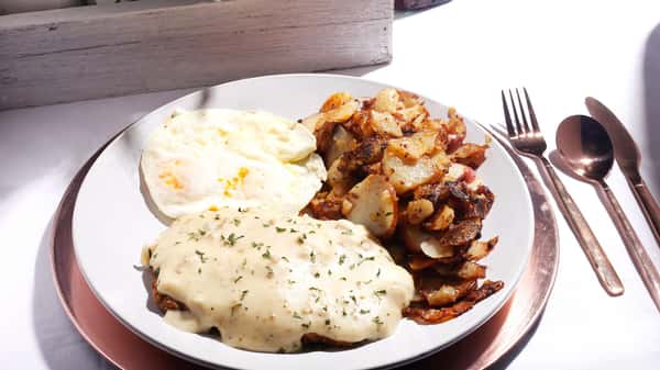 Southern breakfast with chicken-fried steak, biscuit, and potatoes.