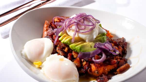 Poached eggs with beans, avocado, and red onions in a breakfast bowl.