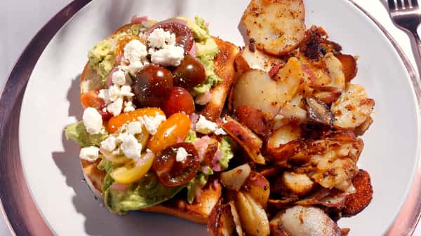 Breakfast plate with salad, feta cheese, tomatoes, and roasted potatoes.