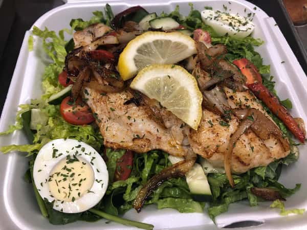 salad topped with grilled fish, hard boiled egg and lemon