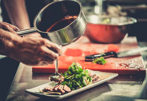 Chef pouring over sauce on food