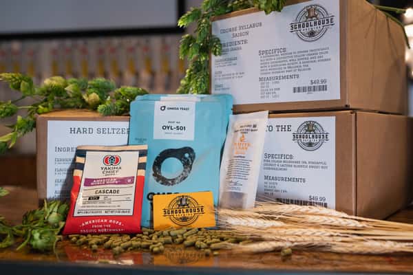 Homebrew ingredient and yeast packets from the Schoolhouse Brewing homebrew shop beside fresh hops