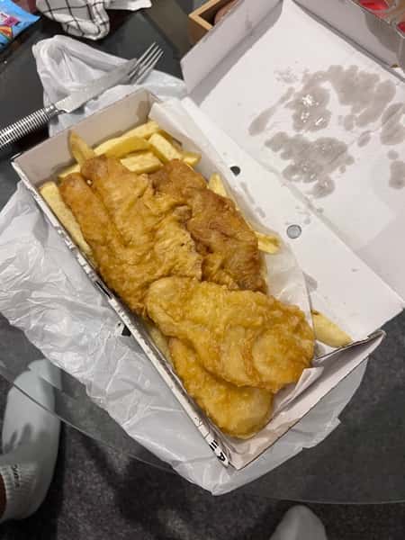 Freshly cooked battered fish served with chips in a takeaway box at Blue Bay.
