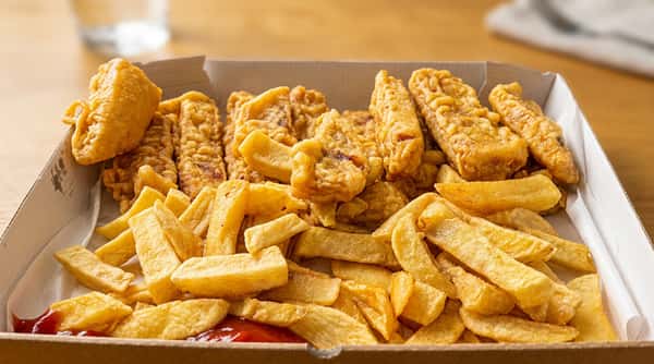 Crispy fish fillet with fluffy white fish inside, served with chips and lemon.