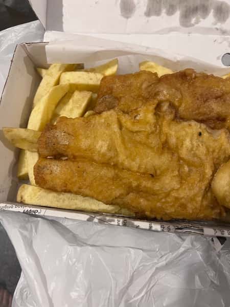 Large golden battered fish fillet served over chips at Blue Bay in Glasgow.