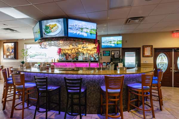 Modern Caribbean bar with high-top seating, illuminated liquor display, and multiple flat-screen TVs—ideal for enjoying tropical cocktails and vibrant nightlife.