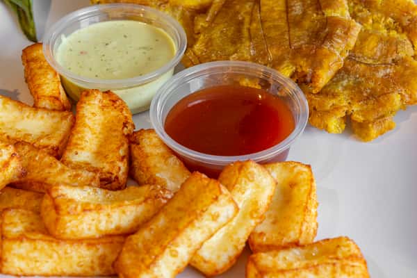 Close-up of crispy fried cheese and golden tostones with dipping sauces—irresistible Dominican snack or side dish.