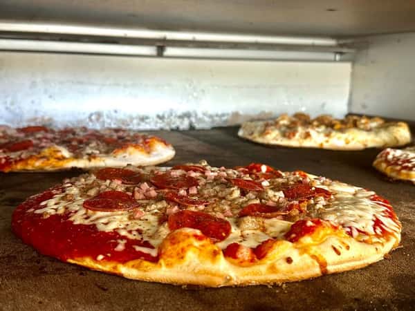 Pepperoni and sausage pizzas baking on a stone oven surface with golden crusts and melted cheese.