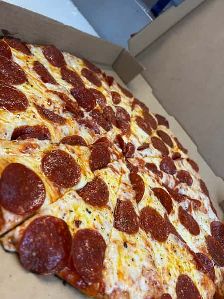 Freshly baked pepperoni pizza in a box, topped with melted cheese and evenly spaced pepperoni slices.