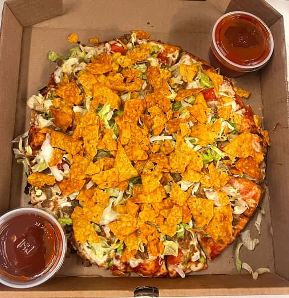 Taco pizza topped with shredded lettuce, crushed Doritos, diced tomatoes, and served with two cups of salsa.