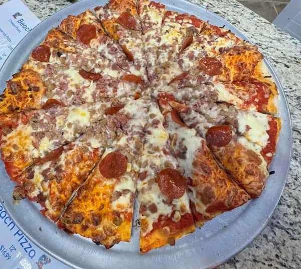 Large meat lover's pizza topped with pepperoni, sausage, ham, and melted cheese on a silver serving tray.