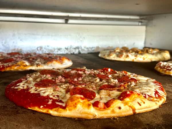 Assorted pizzas baking in a stone oven, featuring pepperoni, sausage, and melted cheese on golden crusts.
