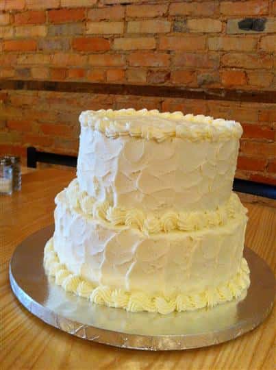 Two tier cake with vanilla and light yellow frosting.
