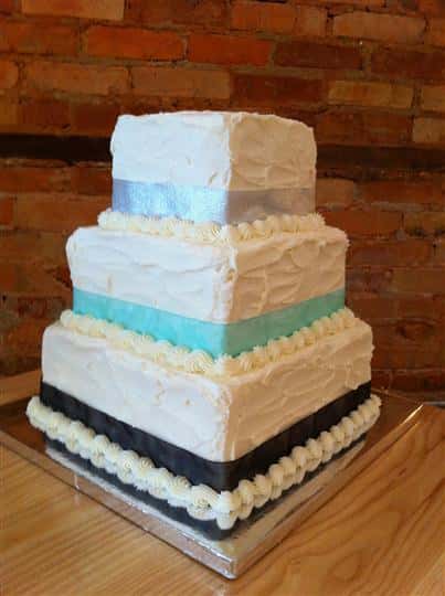Three tier square cake with silver, light blue and black strips.