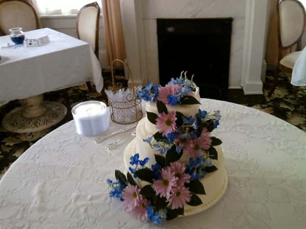Three tiered white cake with pink an blue flowers.